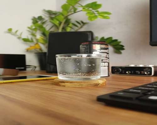 A clean workspace with an ergonomic chair and a glass of fresh water